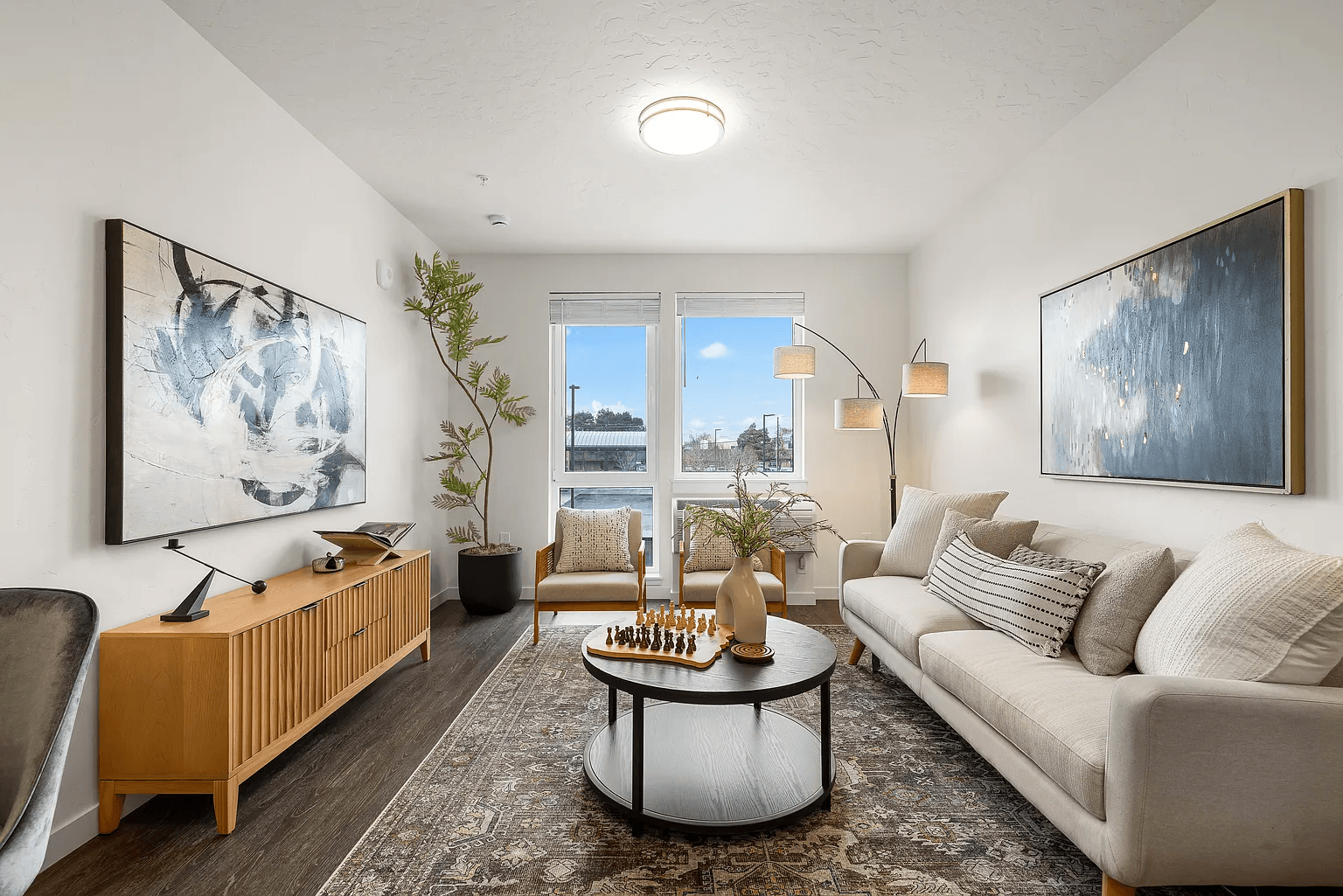 A living room with a couch, a chair, a coffee table, and two paintings on the wall.